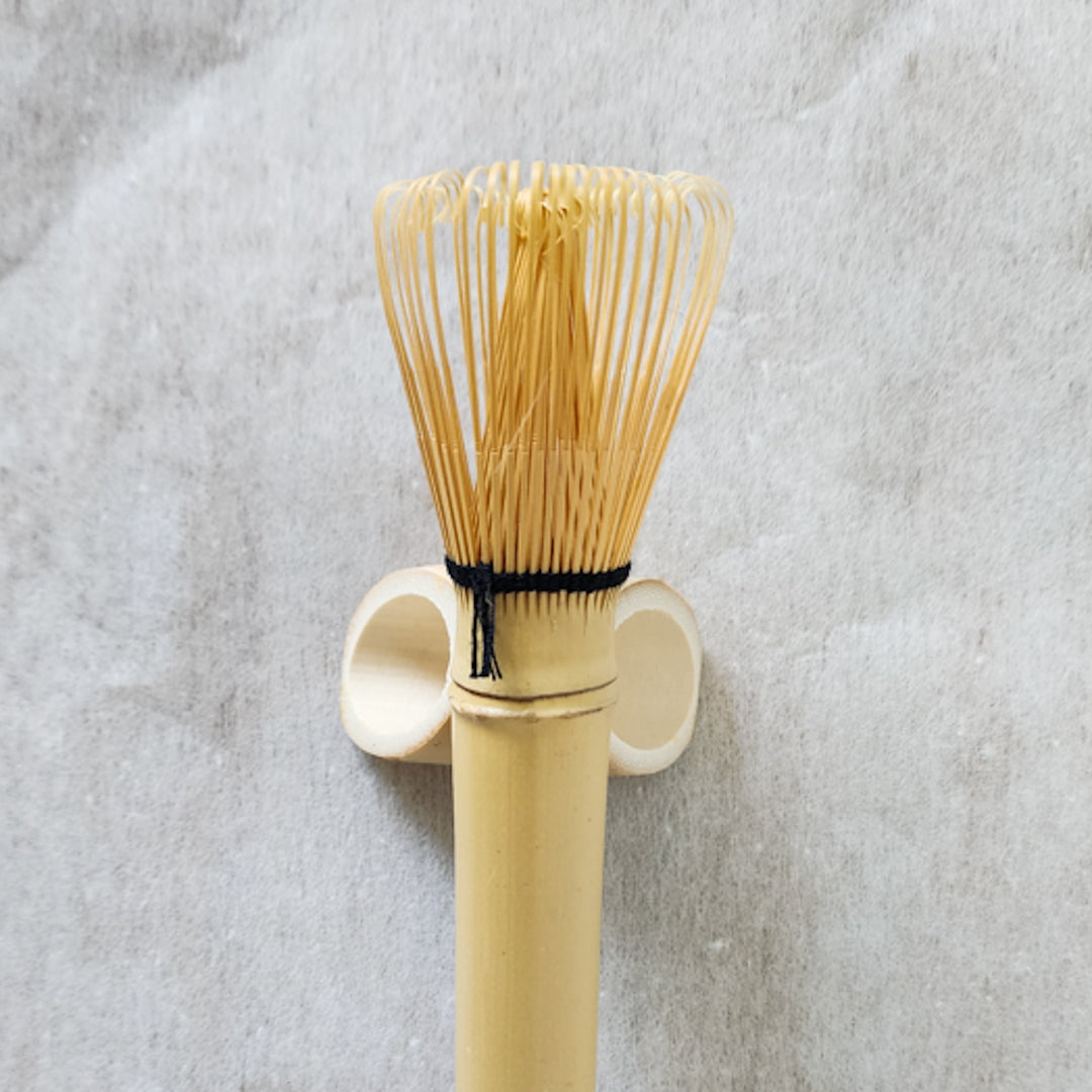 Japanese matcha whisk (chasen) displayed on a traditional holder, essential teaware for matcha lovers