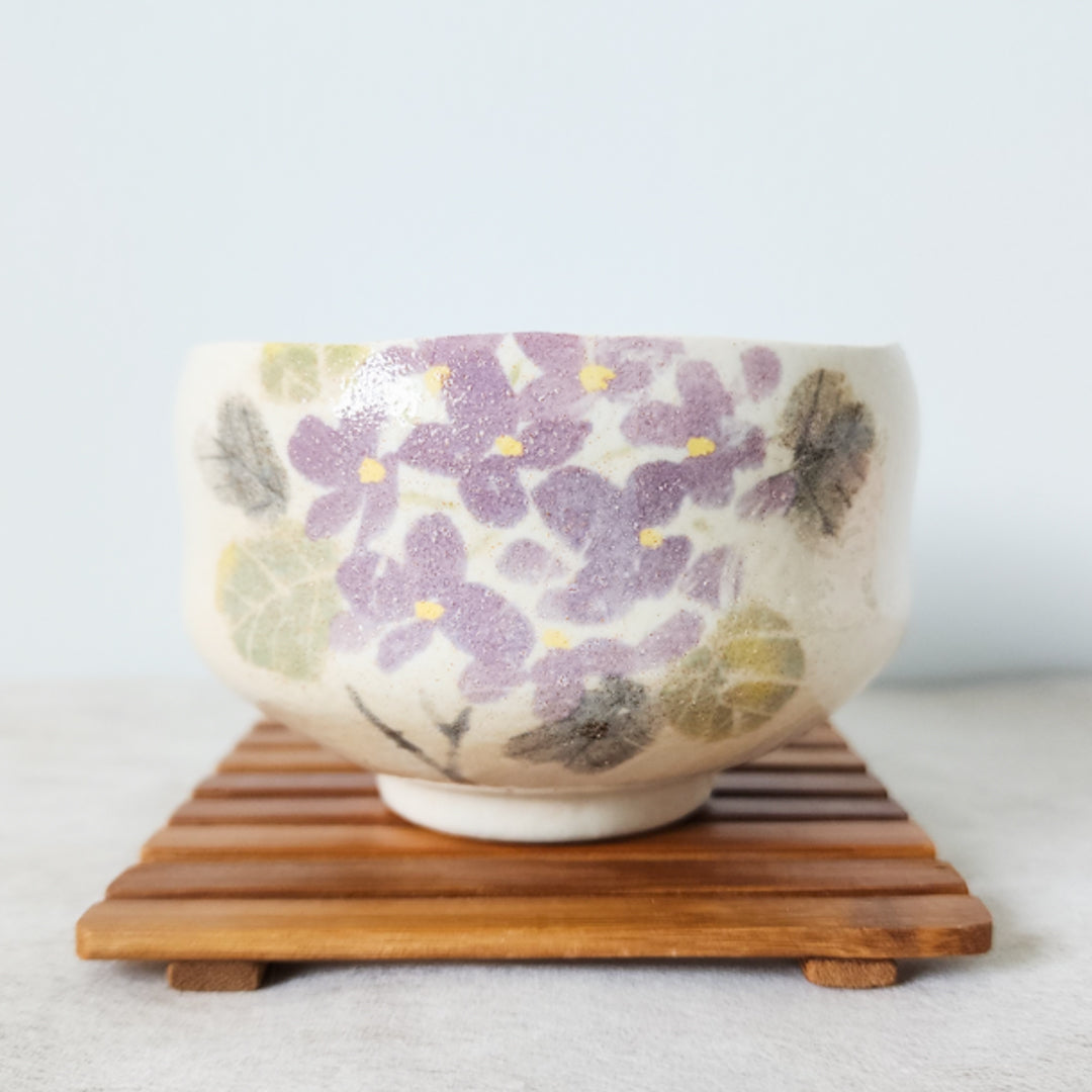 Elegant Japanese chawan with a delicate floral design, sitting on a bamboo coaster, ideal for matcha lovers