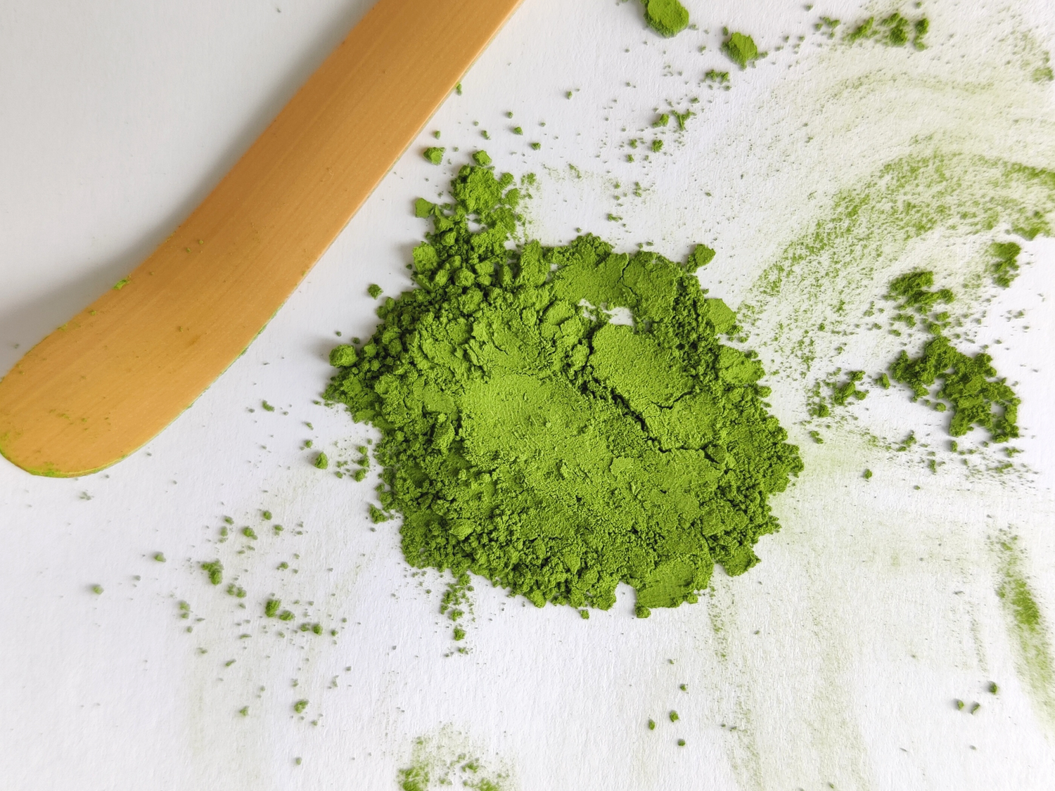 Chashaku (bamboo scoop) placed beside vibrant green matcha powder, essential for traditional Japanese tea preparation