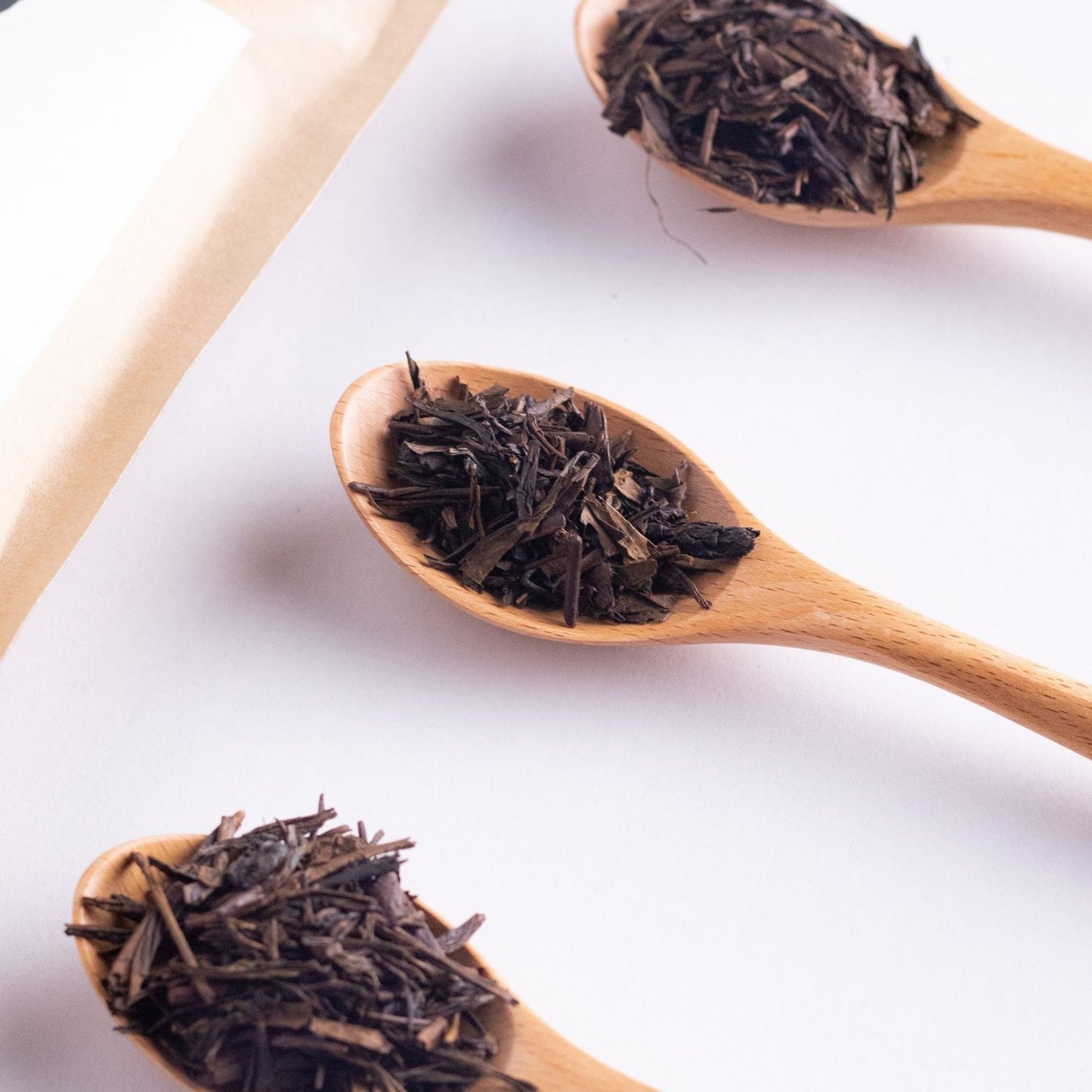 Premium loose leaf tea in Malaysia of roasted Hojicha tea leaves rest on wooden spoons with deep earthy aroma