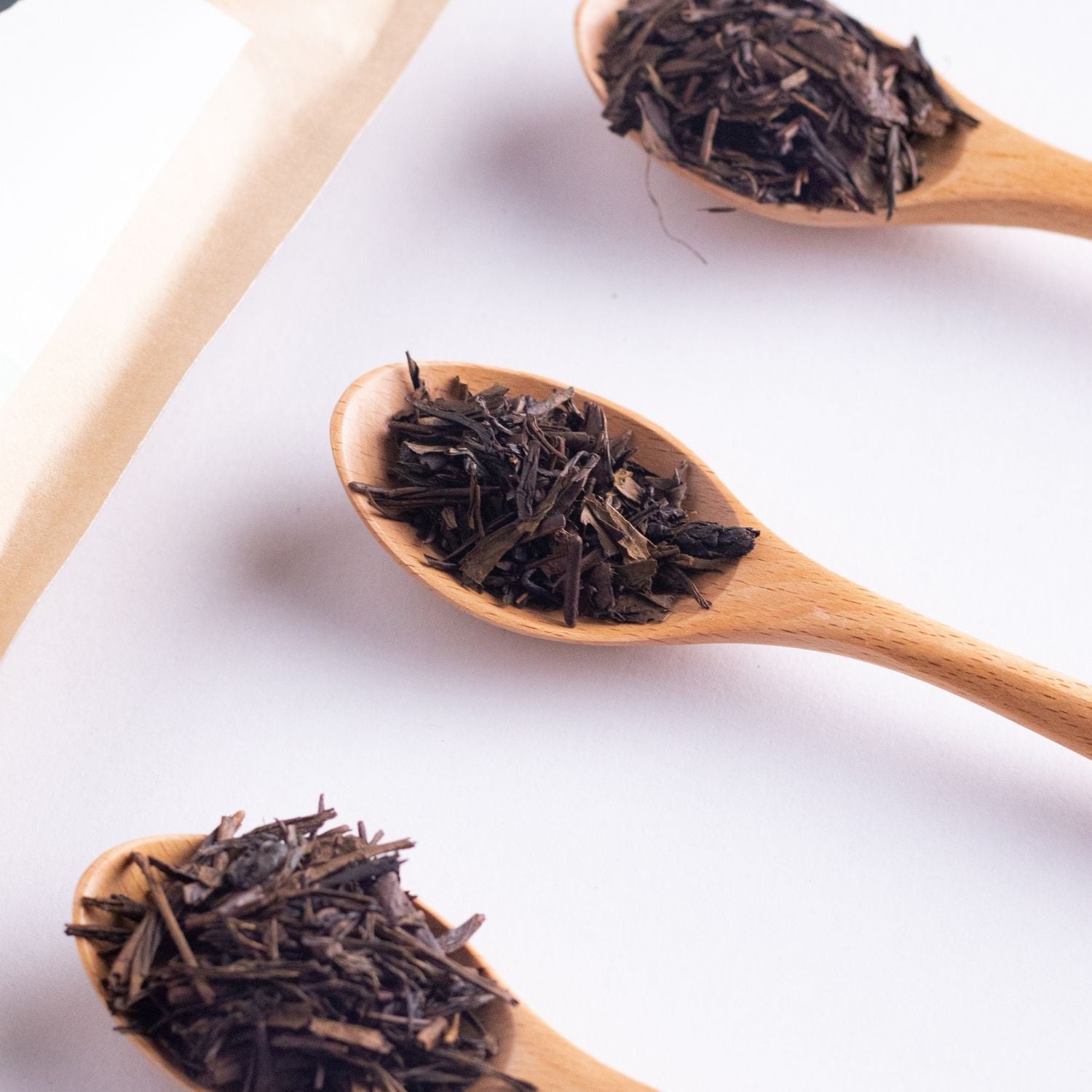 Premium loose leaf tea in Malaysia of roasted Hojicha tea leaves rest on wooden spoons with deep earthy aroma