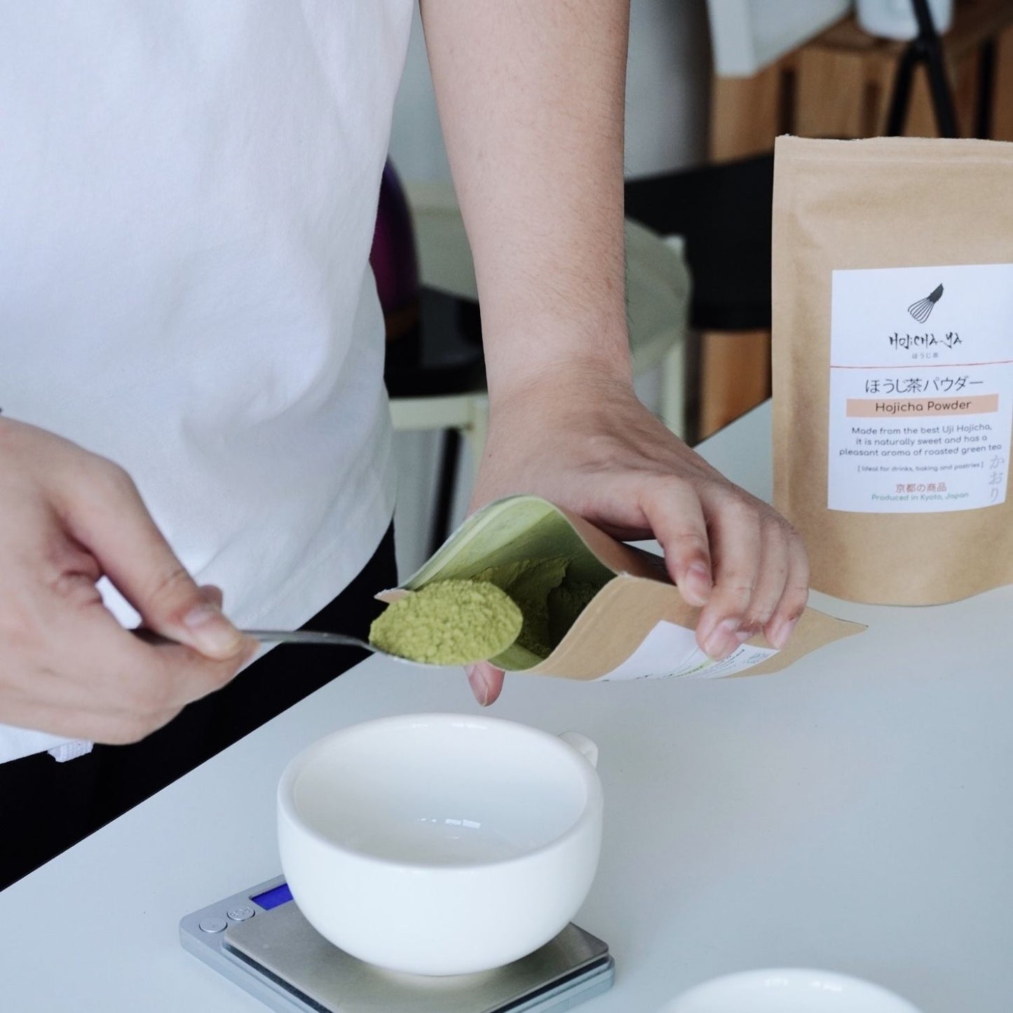 A man is scooping genmaicha powder into the packaging.